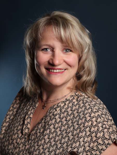 Portrait einer blonden Frau, die freundlich in die Kamera lächelt.